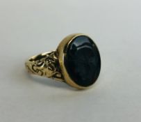 A GENT'S 9CT GOLD SIGNET RING SET WITH A CENTRAL OVAL BLOODSTONE CARVED WITH A CENTURION.