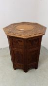 A HARDWOOD ORIENTAL OCTAGONAL FOLDING OCCASIONAL TABLE WITH CARVED FIGURE AND FLOWER DETAILING,