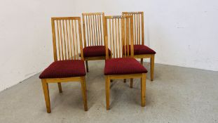 A SET OF FOUR BEECH WOOD FRAMED DINING CHAIRS WITH RED UPHOLSTERED SEATS.