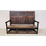 AN EARLY HEAVILY CARVED OAK SETTLE WITH EIGHT CARVED PANELS A/F - LENGTH 177CM. HEIGHT 130CM.