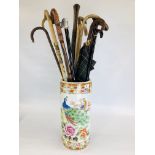 AN ORIENTAL CERAMIC UMBRELLA STAND A/F CONTAINING 12 ASSORTED WALKING STICKS AND UMBRELLAS ETC.