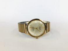 A 9CT GOLD CASED ACCURIST 21 JEWELS SHOCKMASTER ANTIMAGNETIC GENTS WRIST WATCH ON EXPANDABLE STRAP.