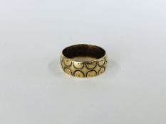 A 9CT GOLD BAND RING WITH ENGRAVED DESIGN.