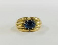 AN IMPRESSIVE DESIGNER YELLOW METAL RING SET WITH A SINGLE CENTRAL RAISED BLUE STONE.