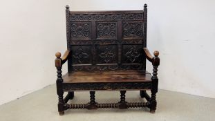AN EARLY HEAVILY CARVED OAK SETTLE WITH SIX PANELS, RING TURNED SUPPORTS AND STRETCHER LENGTH 132CM.
