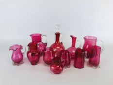 A COLLECTION OF 11 VINTAGE CRANBERRY GLASS JUGS OF VARIOUS DESIGNS AND SIZES.
