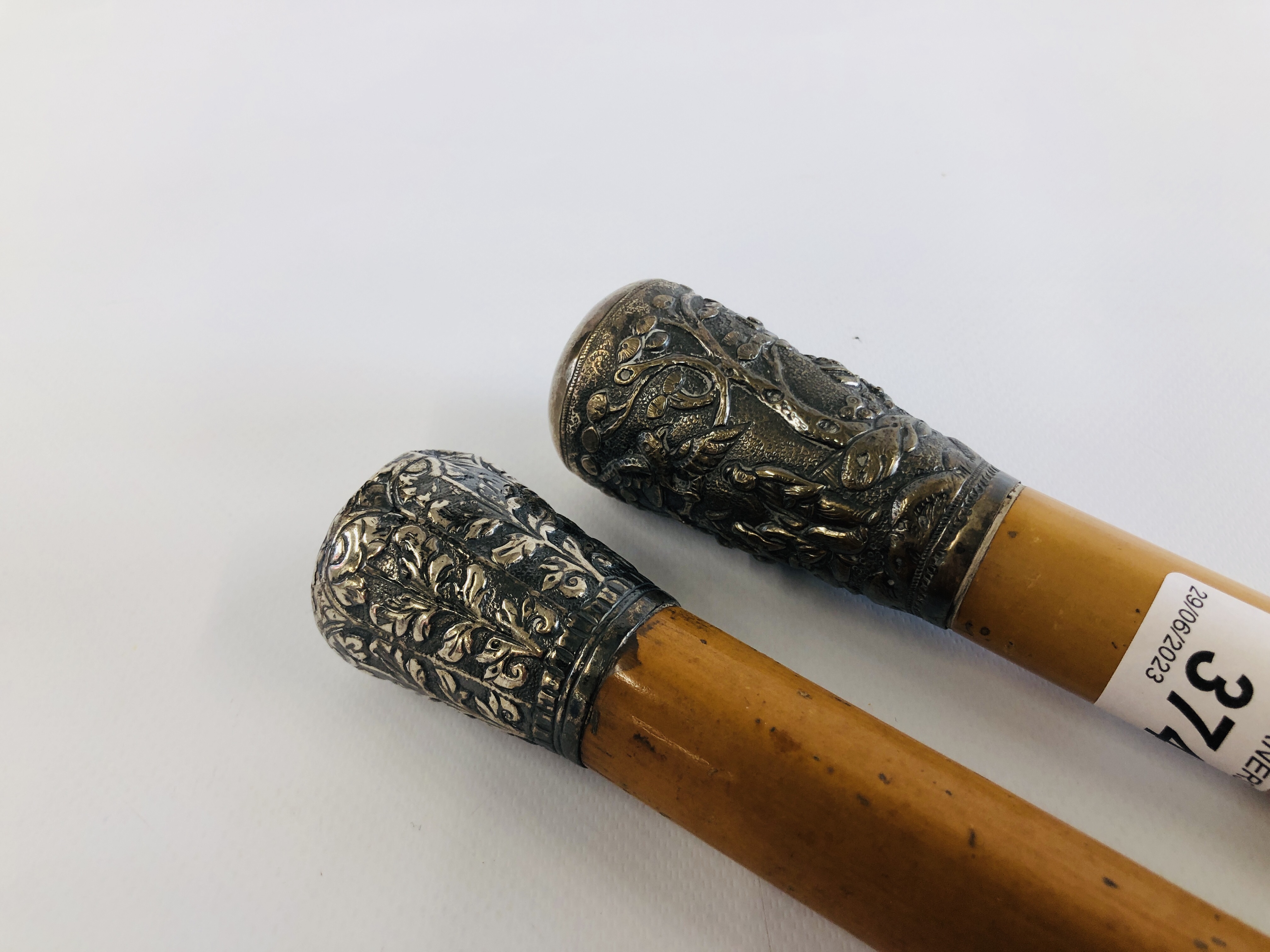 TWO VINTAGE WHITE METAL TOPPED WALKING CANES TO INCLUDE ONE ORIENTAL EXAMPLE.
