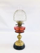 AN ELABORATE ANTIQUE OIL LAMP WITH CRANBERRY GLASS FONT AND BRASS BASE DECORATED WITH ALTERNATING