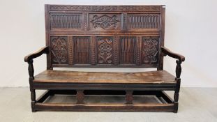 AN EARLY HEAVILY CARVED OAK SETTLE WITH EIGHT CARVED PANELS A/F - LENGTH 177CM. HEIGHT 130CM.