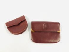 A PURSE MARKED CARTIER ALONG WITH COIN PURSE MARKED CARTIER IN BURGUNDY.