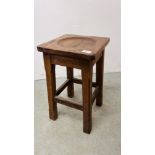 AN ANTIQUE OAK STOOL WITH CARVED CIRCULAR INDENT.