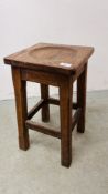 AN ANTIQUE OAK STOOL WITH CARVED CIRCULAR INDENT.