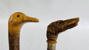 TWO WALKING STICKS TO INCLUDE A HAND CARVED DUCK HEAD EXAMPLE AND A RESIN DOG HEAD HANDLED EXAMPLE.