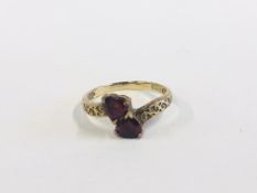 A 9CT GOLD RING SET WITH TWO HEART SHAPE STONES.