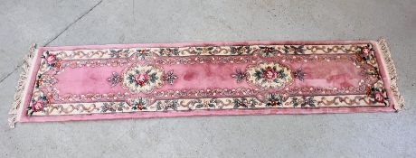 A MACHINE MADE WOOL HALL RUNNER CARPET ON PINK BACKGROUND.