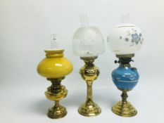 A GROUP OF 3 BRASS OIL LAMPS WITH GLASS SHADES, ONE EXAMPLE HAVING A BLUE CERAMIC FONT.