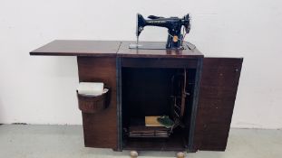 A VINTAGE SINGER SEWING MACHINE AND ACCESSORIES IN A FITTED 2 DOOR CUPBOARD. H 84CM X W 53.