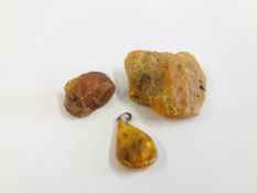 TWO RAW AMBER SPECIMENS ALONG WITH A POLISHED AMBER PENDANT.
