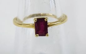 AN 18CT GOLD RING SET WITH A BAGUETTE CUT RUBY (RUBBED MARKS)