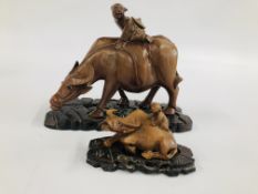 AN ETHNIC HARDWOOD CARVING OF A MAN SEATED UPON A WATER BUFFALO L 20CM + A SMALLER EXAMPLE - BOTH