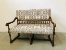 A VINTAGE OAK FRAMED UPHOLSTERED SETTLE HAVING TURNED DETAILING, W 123CM X D 54CM X H 92CM.