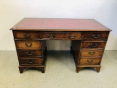 A MAHOGANY NINE DRAWER KNEE HOLE TOOLED RED LEATHER TOP DESK, W 137CM X D 68CM X H 77CM.
