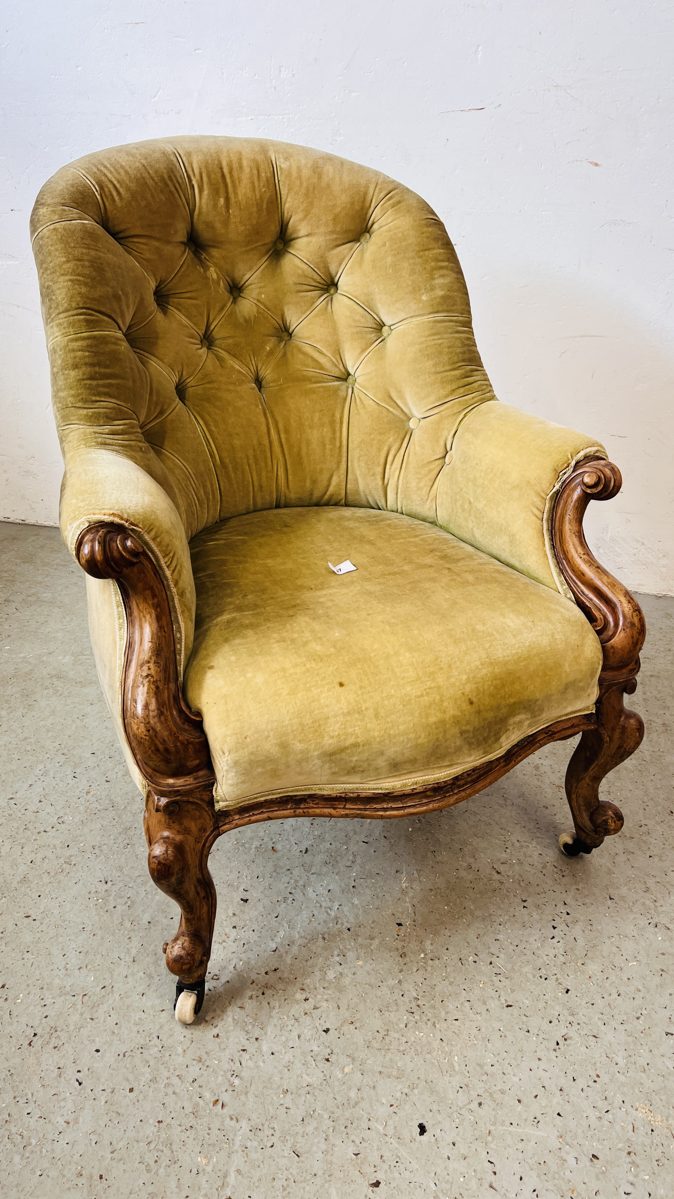 A VICTORIAN MAHOGANY FRAMED BUTTON BACK NURSING CHAIR ON CERAMIC CASTERS.