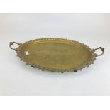 AN ANTIQUE 2 HANDLED BRASS TRAY WITH EMBOSSED AND PIERCED DETAILING STANDING ON 4 PAD FEET 68CM L X