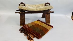 A VINTAGE STYLE CAMEL SADDLE FOOTSTOOL AND TASSELED THROW.