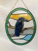 AN OVAL STAINED GLASS HANGING DEPICTING A KINGFISHER - H 42 X W 34CM.