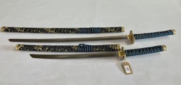 TWO DECORATIVE SAMURAI SWORDS IN SHEATHS UPHOLSTERED IN BLUE AND GOLD - NO POSTAGE.