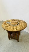 A TEAK HOT PLATE TABLE 90CM DIAMETER FITTED WITH RED HOT PLANCH SYSTEM - MODEL 7H-002.