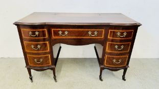 AN ANTIQUE MAHOGANY & INLAID BOW FRONT 7 DRAWER DESK WITH BRASS HANDLES W 136CM X D 65CM X H 85CM.