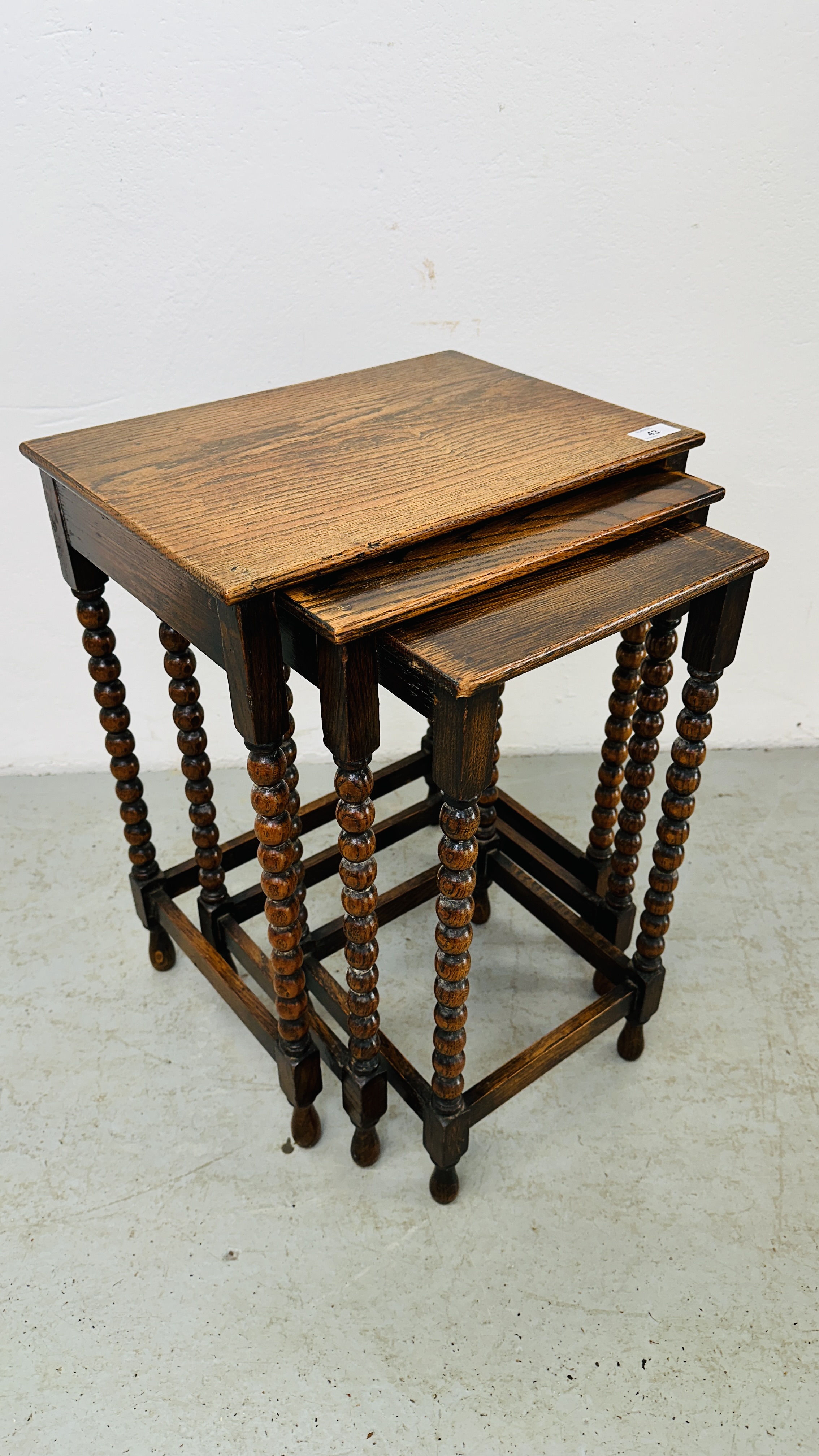 A NEXT TO 3 GRADUATED OCCASIONAL TABLES ON BOBBIN TURNED SUPPORTS - H 55CM X W 42CM X D 30CM.