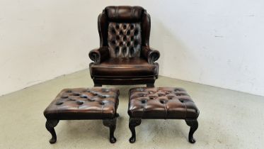 A BROWN LEATHER BUTTON BACK WING BACK FIRESIDE ARMCHAIR ALONG WITH A PAIR OF MATCHING FOOTSTOOLS.