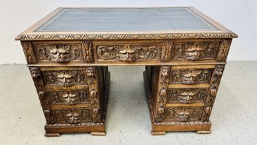 A CARVED OAK PEDESTAL DESK, THE HANDLES IN THE FORM OF THE GREEN MAN, 120CM WIDE X 75CM D X 75CM H.