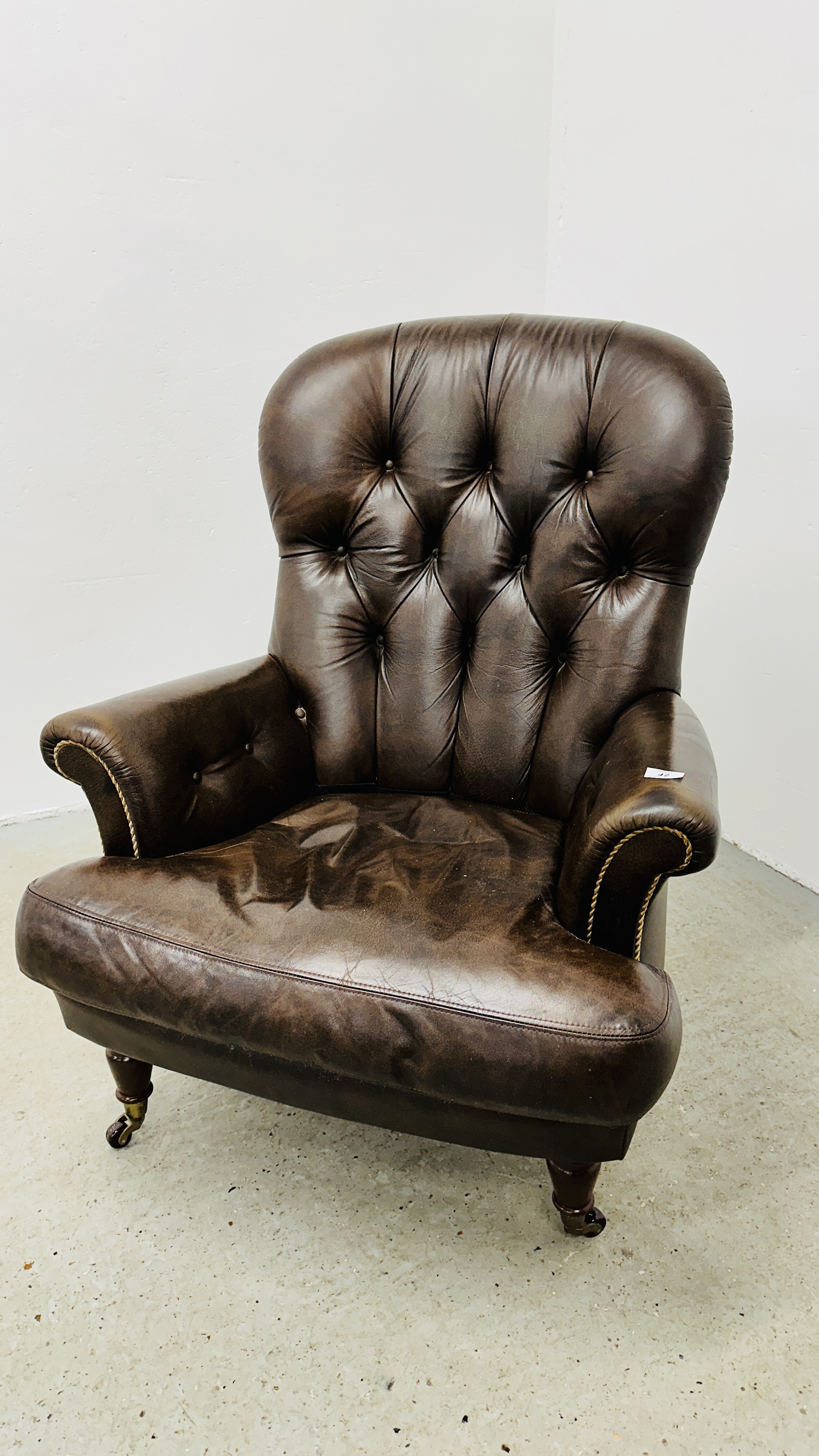 A MODERN TAN LEATHER BUTTON BACK EASY CHAIR.