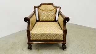AN ANTIQUE LOW CHAIR ON BALL AND CLAW FEET WITH GRIFFIN CARVED DETAIL.