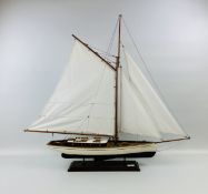 A MODEL SAILING YACHT ON RECTANGLE WOODEN STAND.