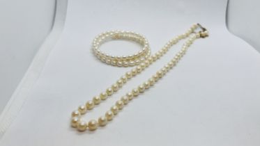 A PEARL STRAND NECKLACE WITH A 9CT GOLD CLASP AND SAFETY CHAIN AlONG WITH A PEARL BRACELET.
