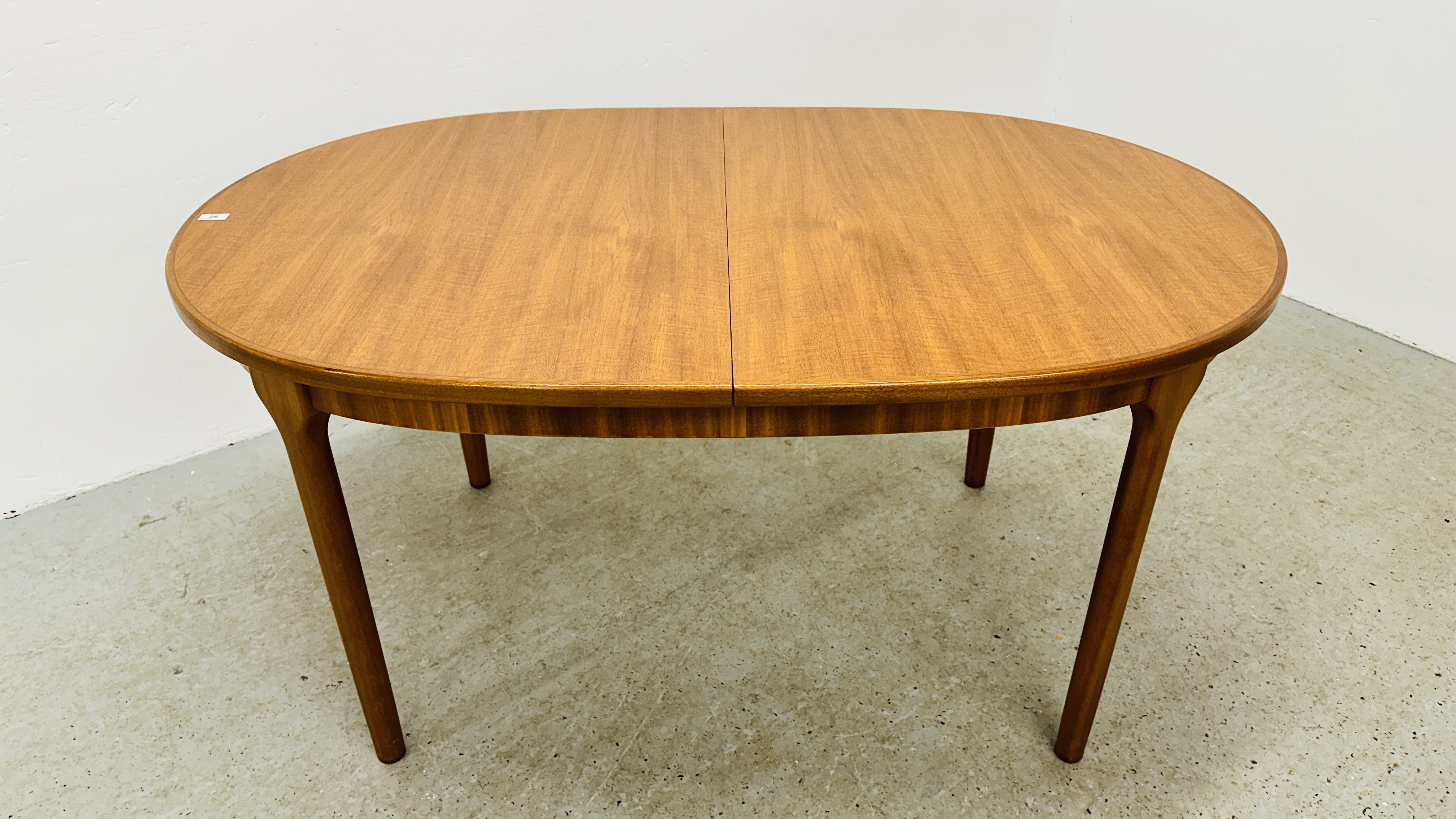 A MID CENTURY TEAK FINISH OVAL EXTENDING DINING TABLE BEARING ORIGINAL MAKERS LABEL "A.H.