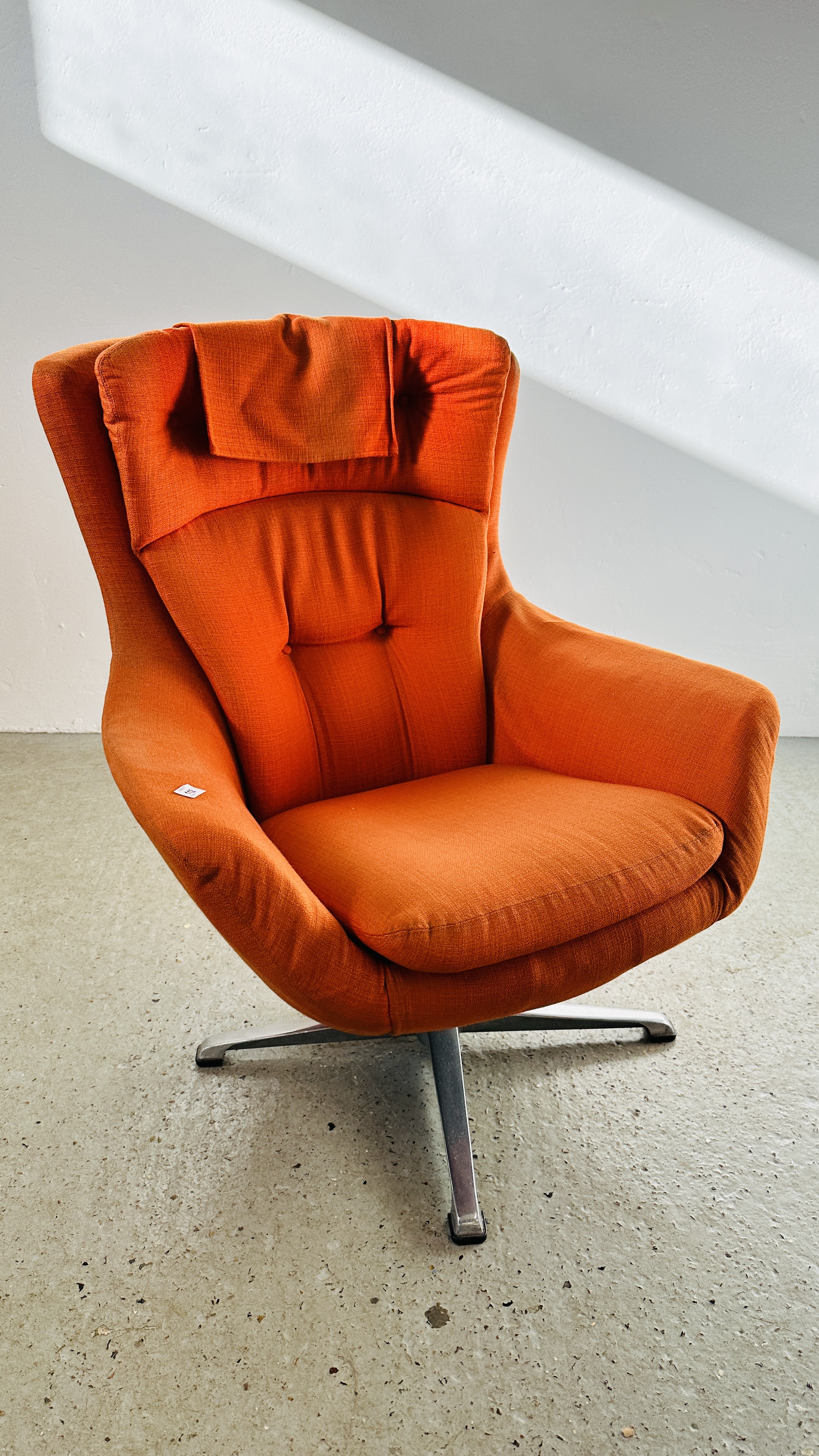 A MID CENTURY RETRO REVOLVING BUCKET RELAXER CHAIR UPHOLSTERED IN BURNT ORANGE.