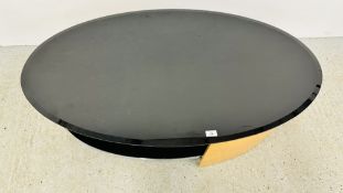 A MODERN DESIGNER FLORENCE OVAL COFFEE TABLE WITH PIANO BLACK GLASS TOP AND SHELF OAK FINISH.