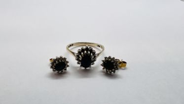 A 9CT GOLD FLOWER HEAD RING SET WITH CENTRAL BLUE STONE SURROUND BY SMALLER CLEAR STONES ALONG WITH