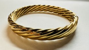 A 9KT GOLD HINGED BANGLE OF TWISTED DESIGN.