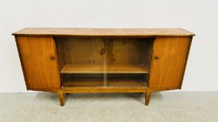 A SOLID TEAK TWO DOOR SIDEBOARD WITH CENTRAL TWO TIER SHELF BEHIND TWO SLIDING GLASS DOORS,