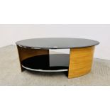 A MODERN DESIGNER FLORENCE OVAL COFFEE TABLE WITH PIANO BLACK GLASS TOP AND SHELF OAK FINISH.