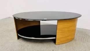 A MODERN DESIGNER FLORENCE OVAL COFFEE TABLE WITH PIANO BLACK GLASS TOP AND SHELF OAK FINISH.