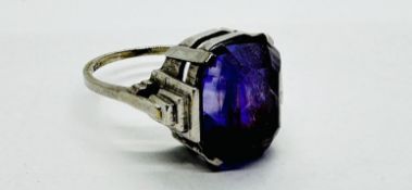 AN ART DECO 9CT WHITE GOLD RING SET WITH A LARGE CENTRAL PURPLE STONE. SIZE O/P.