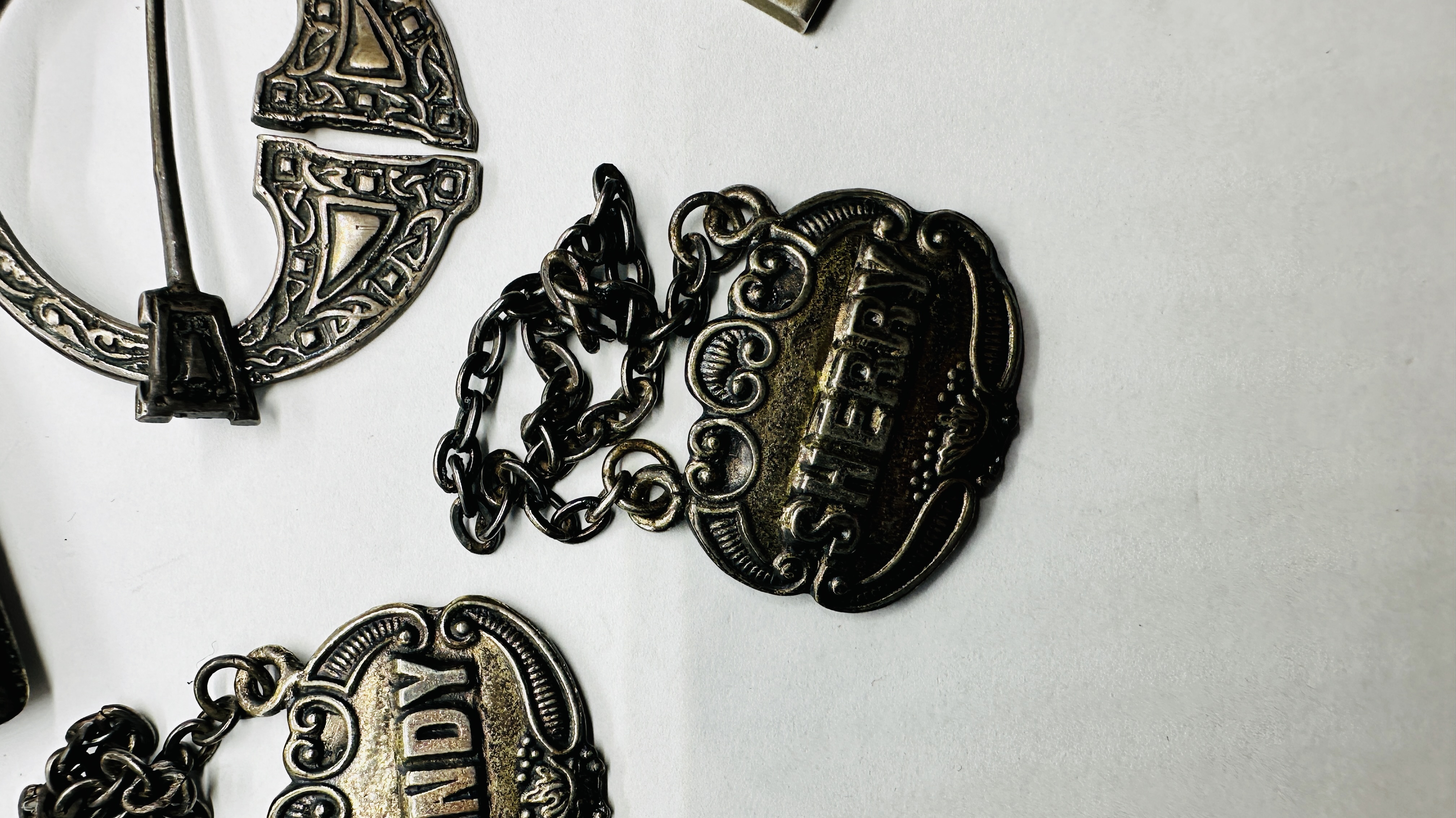 A SILVER CELTIC STYLE BROOCH, INGOT & 3 PLATED DECANTER LABELS, 2 X NAPIN RINGS, - Image 2 of 11